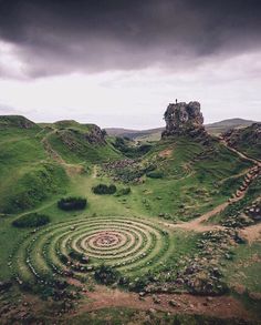 an aerial view of a grassy area with a spiral design in the middle and a rock outcropping at the top