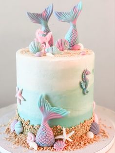 there is a cake decorated with blue and pink mermaids on the top, along with other decorations