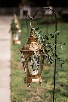 an old fashioned lamp hanging from a pole with olives on it's side