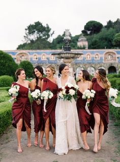 a group of women standing next to each other in front of a building and holding bouquets