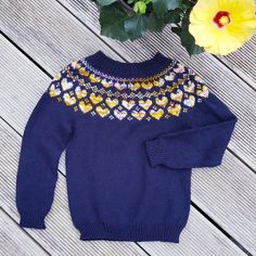 a blue sweater sitting on top of a wooden floor next to a potted plant