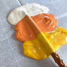 an orange, yellow and white paint is being used to make the top of a piece of cake