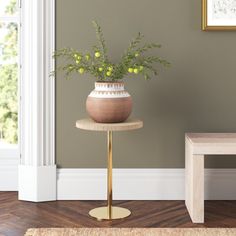 a small table with a vase on it next to a bench