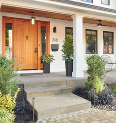 the front entrance of a home with steps leading up to it and potted plants on either side