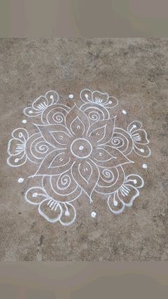 a drawing on the ground that looks like it is made with white chalk and has an intricate flower design