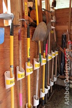 there are many different tools hanging on the wall in this shed, including shovels and rakes