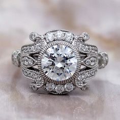 a white gold ring with an oval cut diamond surrounded by smaller round diamonds on a marble surface