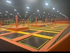 an indoor trampoline park with lights on the ceiling and yellow safety barriers around it