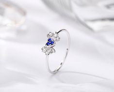 "CUPID, the heart engagement ring with blue sapphire and diamond. Dainty angel wings design in white gold. * Sweet and angelic * 3D heart with volume and dimension * Dainty look for everyday * Genuine Sri Lanka blue sapphire * Genuine diamond, conflict-free * Diamond accents on shoulder * Solid 14k white gold * Great as alternative engagement ring * Original art engraved wood box * Free shipping worldwide CONCEPT CUPID ring, a winged heart symbolize Cupid, the God of love and affection. Wear thi Blue Diamond Heart Ring For Wedding, Elegant Sapphire Heart Ring As A Gift, Dainty White Gold Sapphire Ring For Wedding, Elegant Blue Heart Ring For Anniversary, White Sapphire Cubic Zirconia Ring Gift, White Sapphire Ring With Brilliant Cut For Gift, White Sapphire Ring With Brilliant Cut As Gift, Elegant Blue Heart Ring For Wedding, White Sapphire Cubic Zirconia Promise Ring