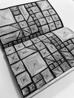 an open book with black and white designs on it's cover, sitting on a table