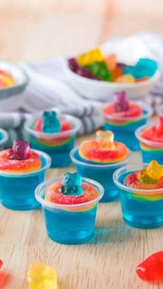 small plastic cups filled with gummy bears on top of a wooden table