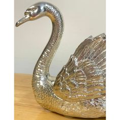 a silver swan figurine sitting on top of a wooden table