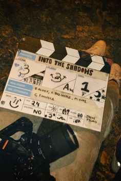 a movie clapper sitting on the ground next to some shoes