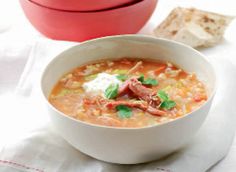 a white bowl filled with soup next to a red container on top of a table