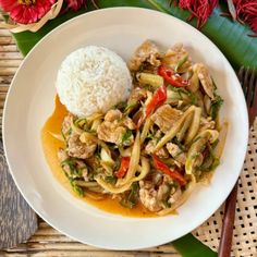 a white plate topped with meat and veggies covered in sauce next to rice