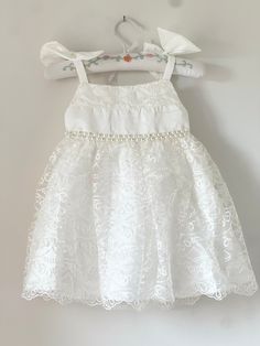 Beautiful and elegant baby girls' lace baptism dress. Features pearl and gem accents at the waist. Complete with a linen and cotton blend liner, to ensure comfort. First Communion Lace Dress For Pageant, Lace First Communion Dress For Pageant, First Communion Lace Dress With Lace Trim For Pageant, Lace First Communion Dress With Lace Trim For Pageant, Sleeveless Lace Bodice Dress For Baptism, Sleeveless Lace Dress With Lace Bodice For Baptism, White Sleeveless First Communion Dress With Lace Bodice, White Sleeveless First Communion Dress With Lace Trim, Sleeveless Lace First Communion Dress With Lace Trim