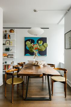 a dining room table with chairs and a painting on the wall