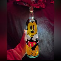 a person holding up a bottle with an image of mickey mouse on it