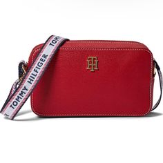 This Tommy Hilfiger Adrienne Ii Camera Crossbody Is A Must-Have For Any Fashion-Forward Woman. With A Pebbled Finish And Red Hardware Accents, This Bag Is Perfect For Any Occasion. The Bag Features A Zip Closure And A White Nylon Handle/Strap For Easy Carrying. This Small-Sized Bag Measures 8 Inches In Width, 5 Inches In Height, And 2 Inches In Depth. It Is Made Of Durable Pvc Exterior Material And Features A Red Fabric Lining. The Bag Also Has Painted Initials For A Personalized Touch. The Mode Painted Initials, Tommy Hilfiger Bags, In Depth, Red Fabric, Fashion Forward, Color Pop, Tommy Hilfiger, Crossbody Bag, Initials