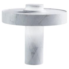 a white marble table with a circular base and an open end section on the top