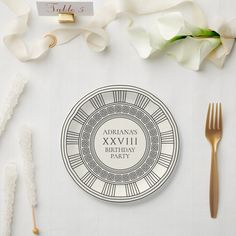 a place setting with white flowers and gold cutlery on the table, along with personalized napkins