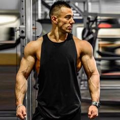 a man standing in front of a gym machine with his hands on his hips and looking at the camera