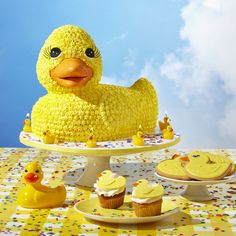 a yellow duck cake and cupcakes on a table