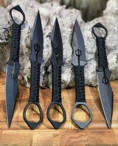 five different types of knifes on a wooden table with rocks in the back ground