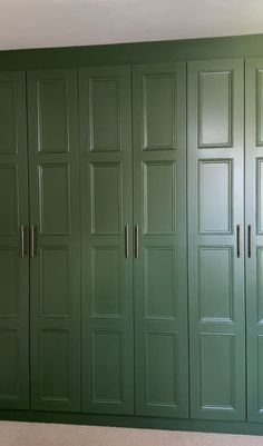 a room with green cupboards and carpeted flooring in front of the wall