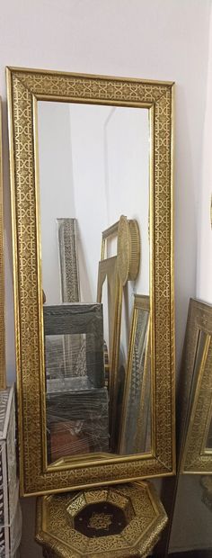 a mirror sitting on top of a wooden table next to a pile of framed pictures