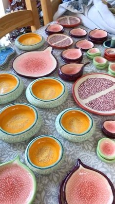 a table topped with lots of colorful plates and bowls filled with different types of fruit