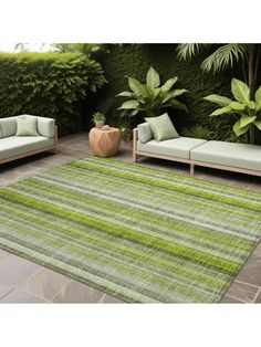 an outdoor area with green and white rugs, couches and potted plants