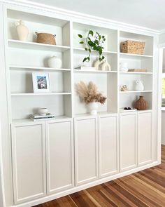 a white bookcase filled with lots of books on top of a hard wood floor