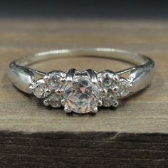 three stone diamond ring sitting on top of a wooden table