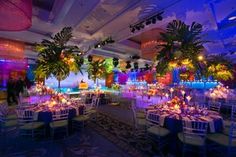 a banquet hall with tables and chairs decorated in blue, yellow and purple lighting is shown