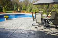 an outdoor dining table and chairs next to a swimming pool with umbrellas over it