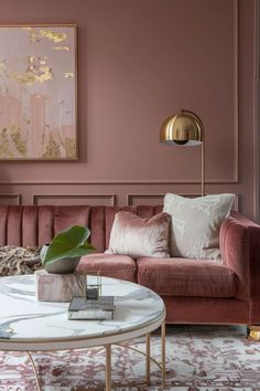 a living room with pink couches, gold accents and a painting on the wall