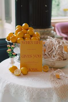 a table topped with lots of oranges next to a sign