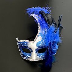 The swan-inspired blue/silver mask for women has arching feathers. Blue Masquerade Mask For Halloween Party, Blue Masquerade Mask For Halloween Costume Party, Blue Masks And Prosthetics For Carnival Costume Party, Blue Masquerade Mask For Halloween, Blue Halloween Masquerade Mask, Blue Masks For Carnival Costume Party, Blue Masquerade Mask For Mardi Gras Costume Party, Blue Masquerade Mask For Mardi Gras Carnival, Blue Masquerade Mask For Carnival Costume Party