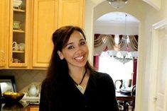 a woman standing in a kitchen holding a glass of wine