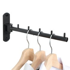 two wooden clothes hangers with black clips on them and one white shirt hanging from the rail