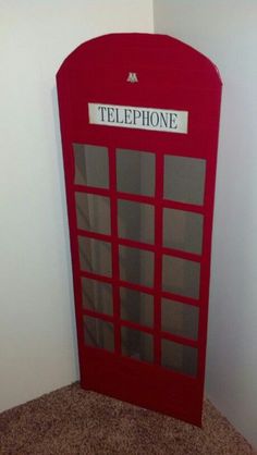 a red phone booth sitting on top of a carpeted floor next to a wall