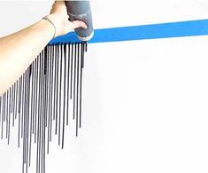 a person using a hair dryer on top of a blue and white striped wall