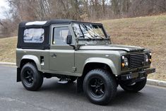 an olive green land rover is parked on the street