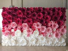 an art piece made out of paper flowers on a table with white and pink colors