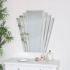 a white dresser with a mirror on top of it next to a potted plant