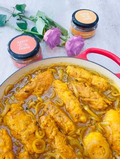 a large pot filled with chicken and onions next to some sauces on the table