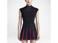 a woman in a black and pink tennis dress is standing with her hands on her hips