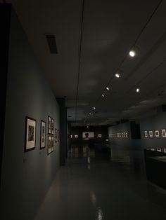 an empty room with pictures on the wall and lights hanging from the ceiling in front of them