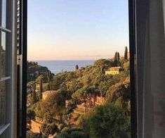 an open window looking out at the ocean and trees in front of it on a sunny day